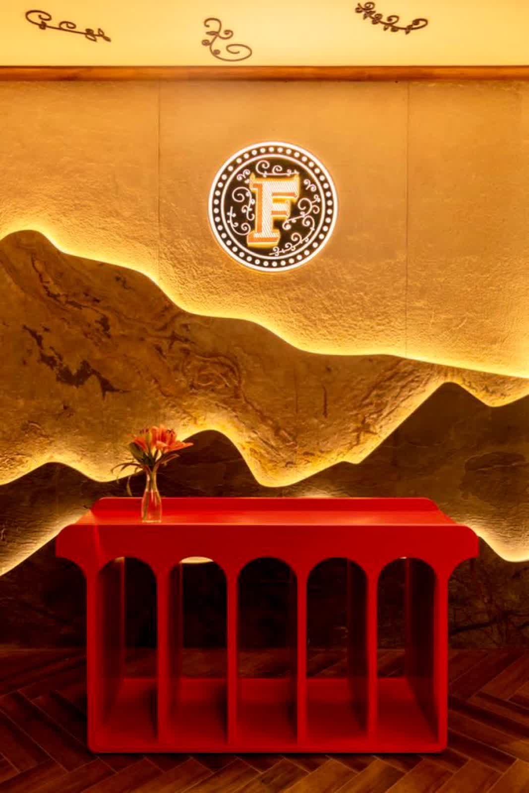 Hand-engraved Farzi F emblem above a red console