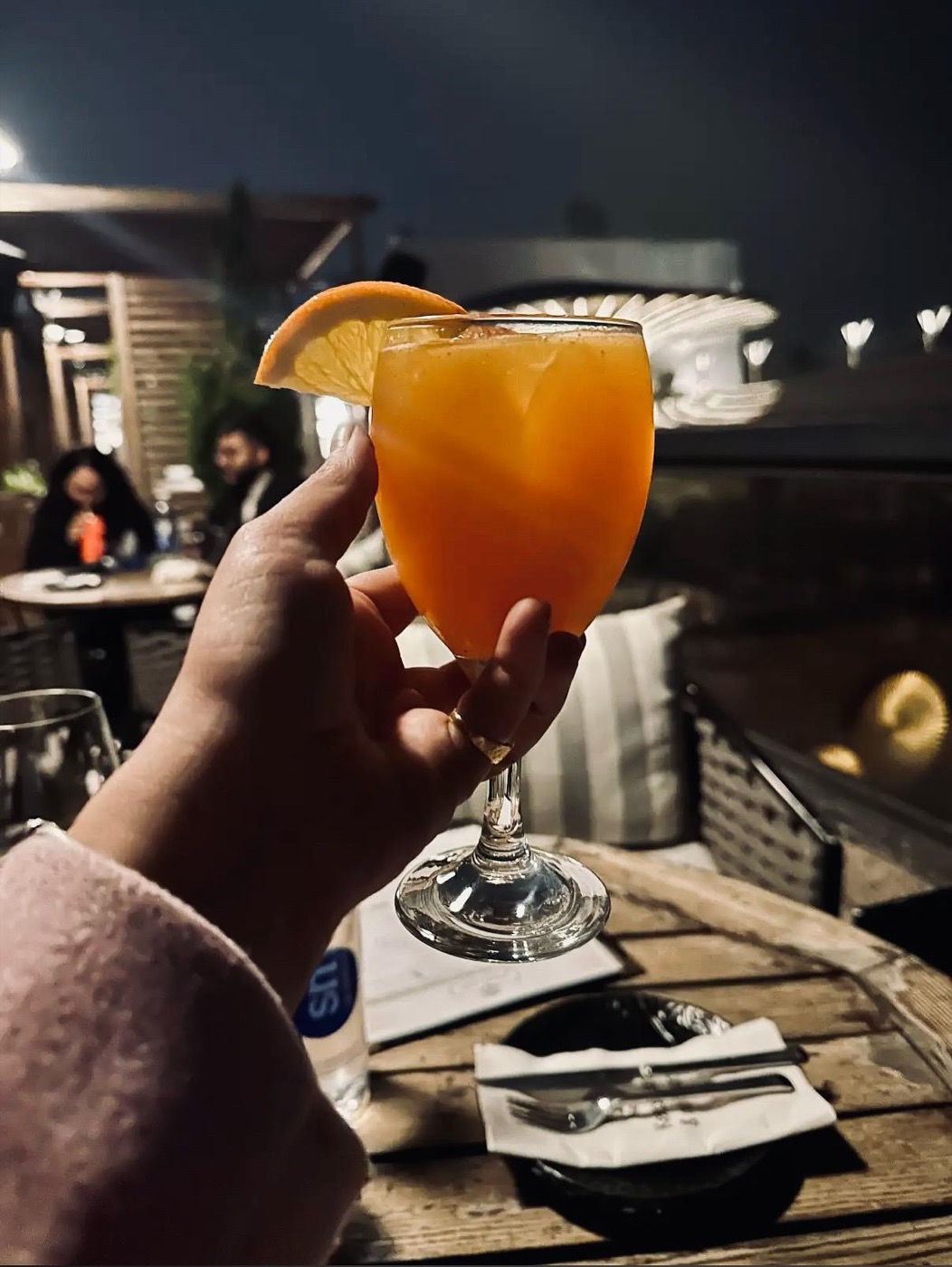 Orange signature cocktail with bar in background